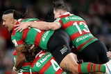 A group of South Sydney NRL players embrace as they celebrate defeating Manly.