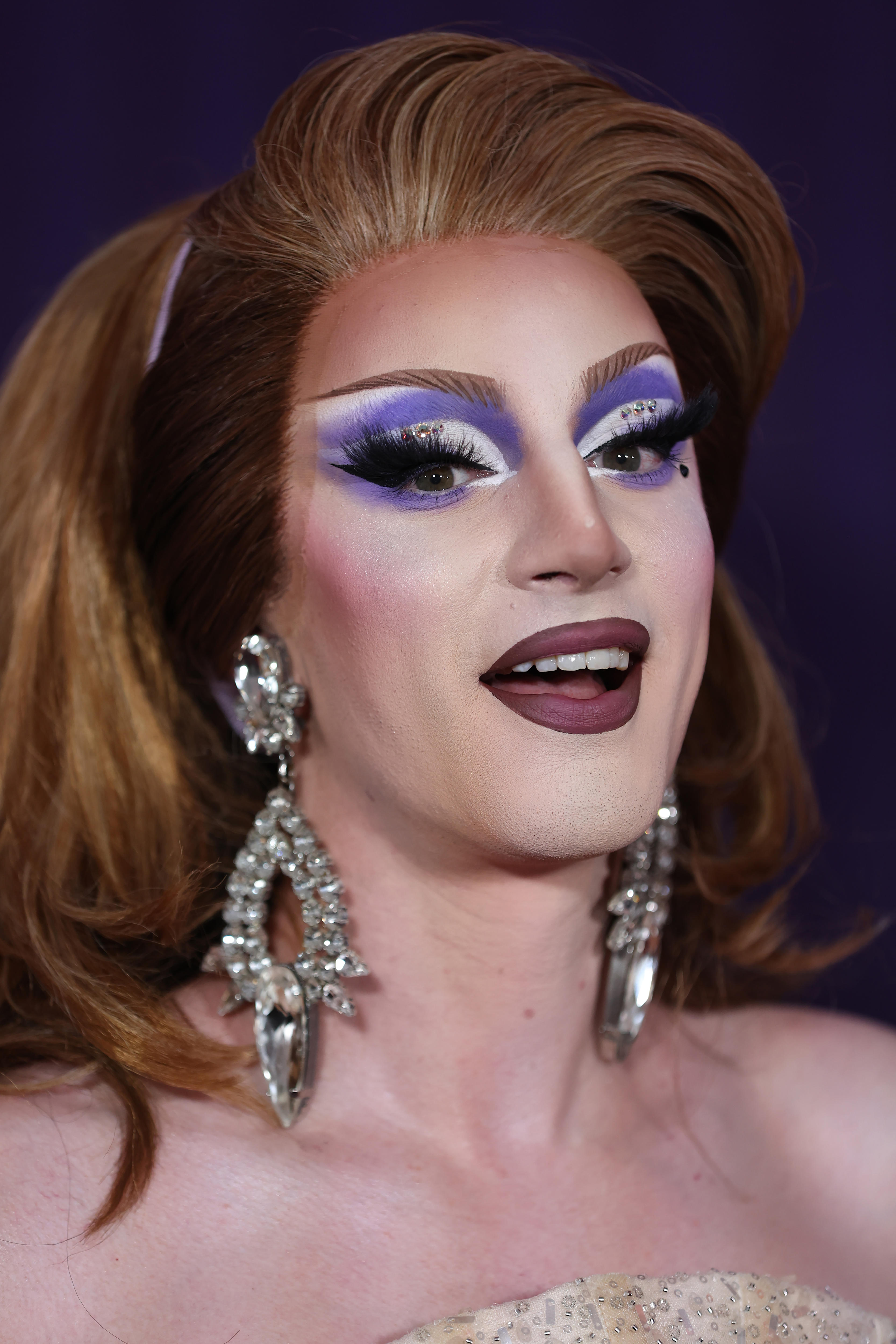 A close up of a drag queen's face and her purple makeup