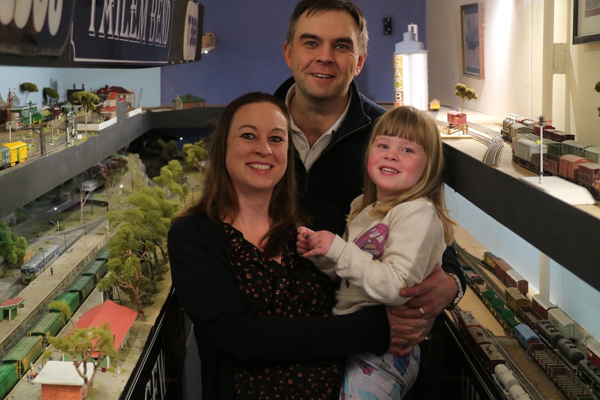 A man, woman and child pose next to a model railway