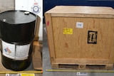 A composite image of a fuel drum standing next to a crate.