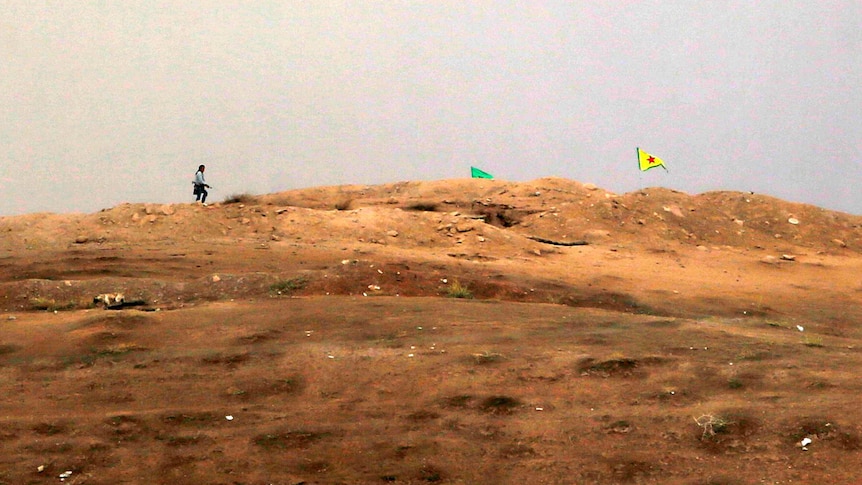 Fighter near Kurdish flag at checkpoint in Kobane