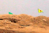 Fighter near Kurdish flag at checkpoint in Kobane