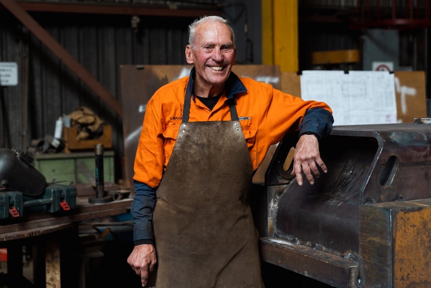 Graham Budd smiling and leaning up against machinery in the workshop.