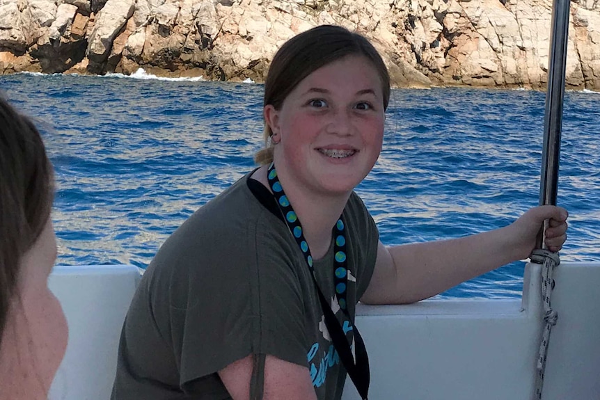 Kate smiles at the camera. She is on a boat, in front of what appears to be a castle or fort.