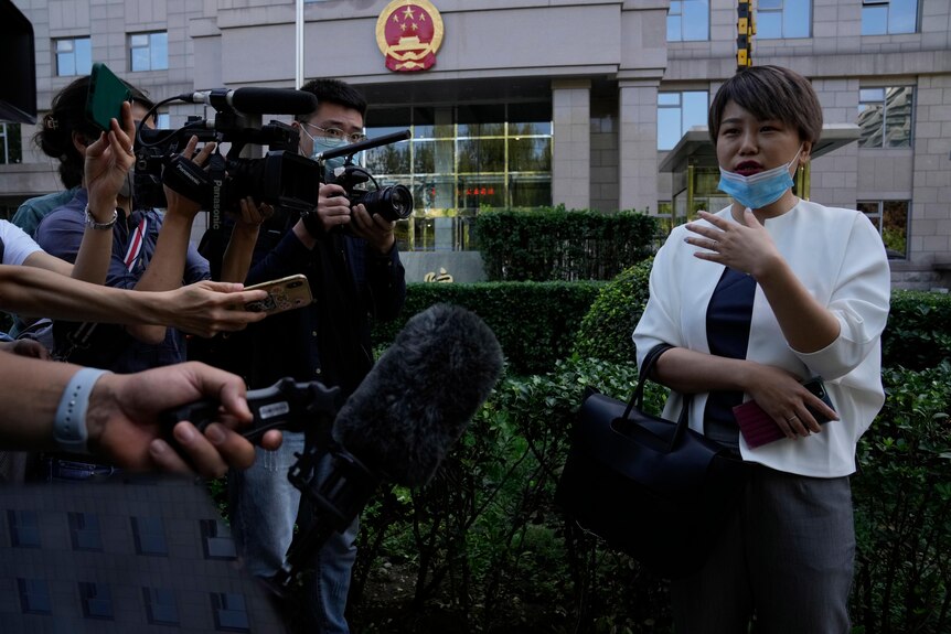 Woman in white jacket speaks to media outside Chinese courthouse.