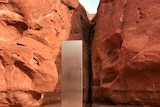 A shiny metal structure stands in a red rock canyon