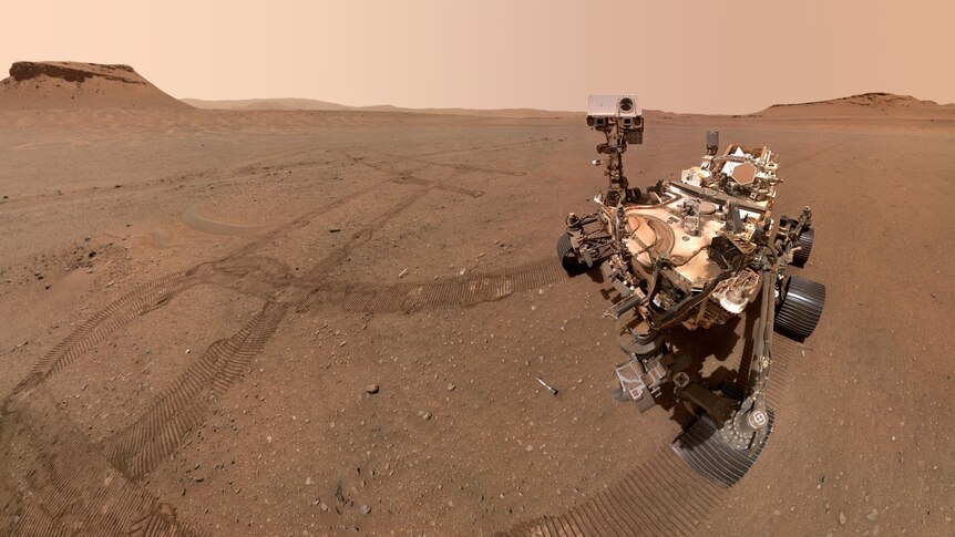 NASA's Perseverance rover appears on the surface of Mars. Tracks are visible in the soil. 