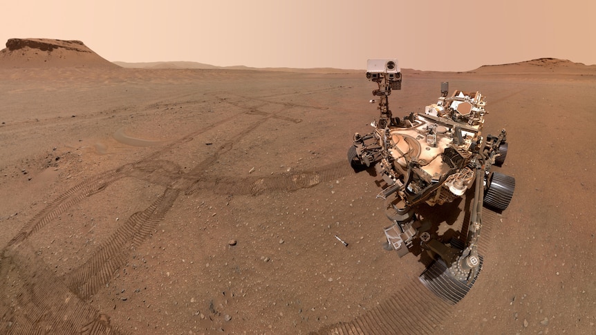 NASA's Perseverance rover appears on the surface of Mars. Tracks and sample tubes are visible in the soil. 