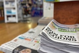 A stack of newspapers in a newsagency with the headline 'win for regions' in foreground