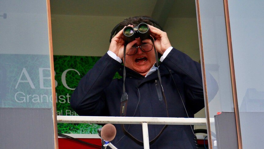 Tim Gavel watches a raiders match through binoculars.