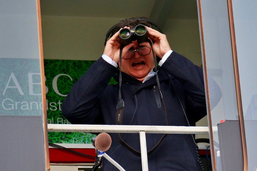 Tim Gavel watches a raiders match through binoculars.