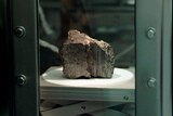 The meteorite sits behind glass in a chamber at the Johnson Spce Center Lab.