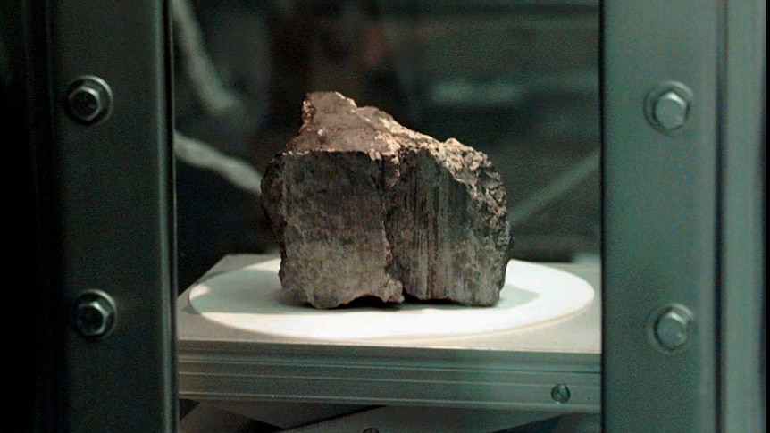 The meteorite sits behind glass in a chamber at the Johnson Spce Center Lab.