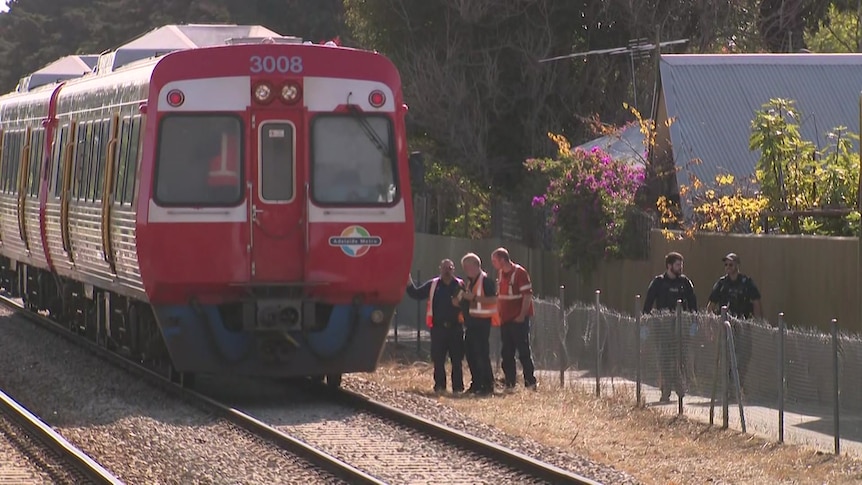 A train with police and three men in fluoro vests standing nearby