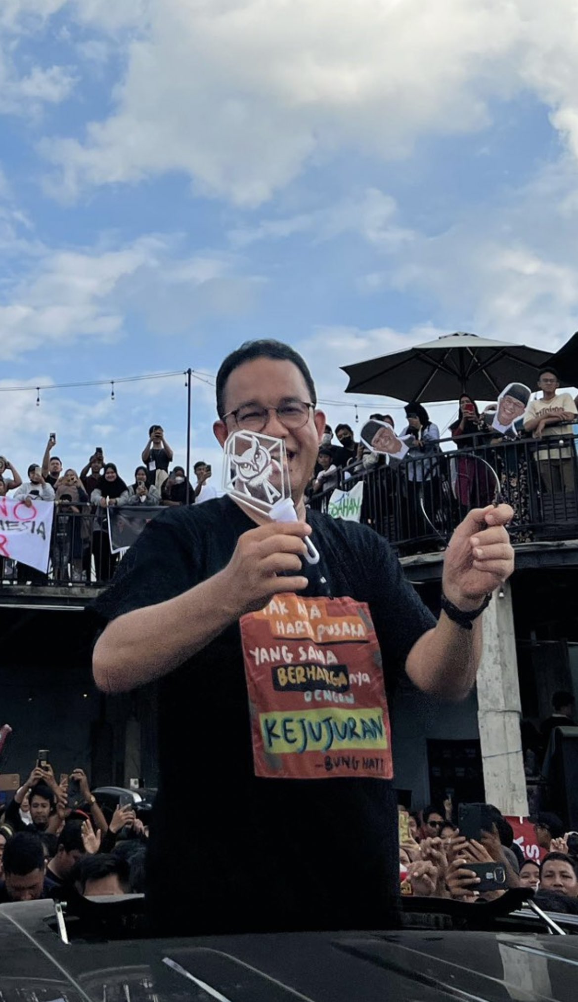 A man holding a lightstick with many people in the background.
