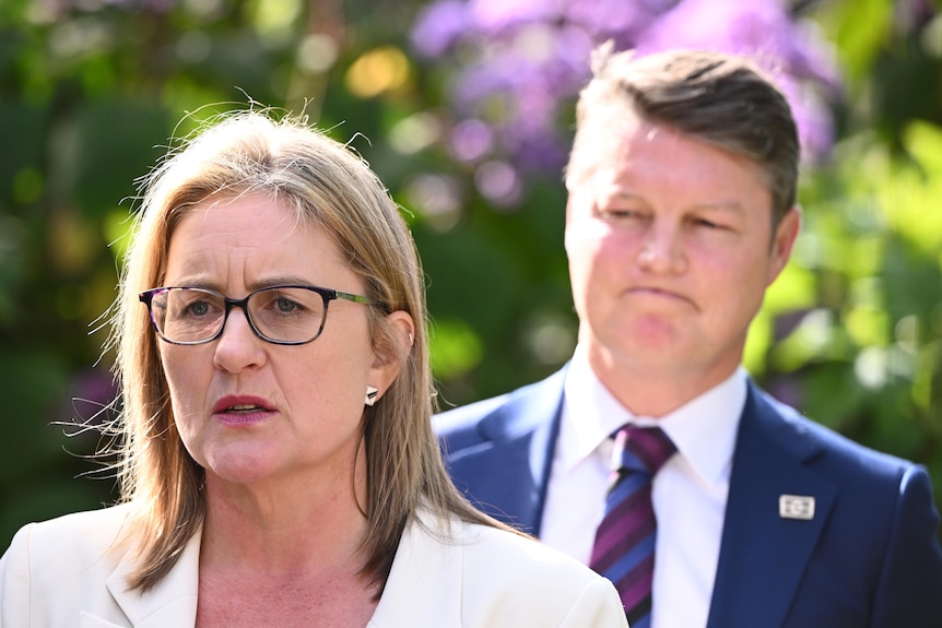 Ben Carroll looks on as Jacinta Allan addresses the media