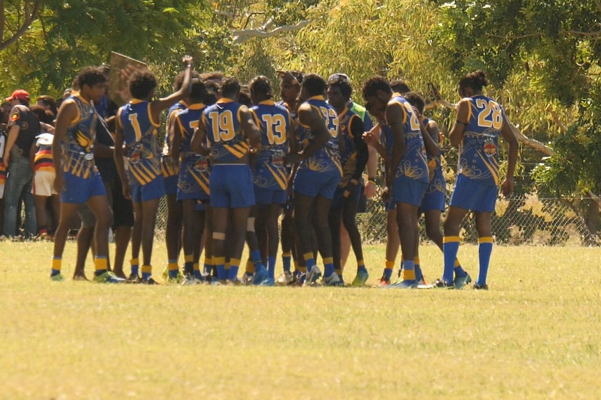 A mostly Indigenous football team huddles