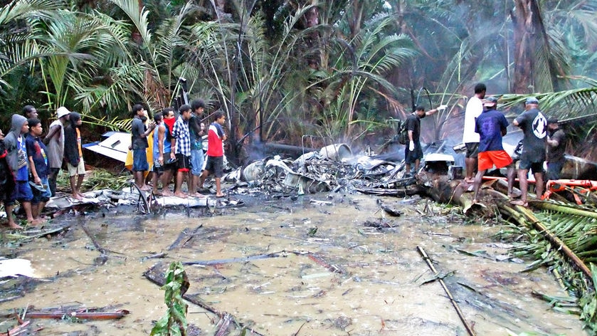 Villagers examine the wreckage of a Trans Air jet that crashed on Misima Island.