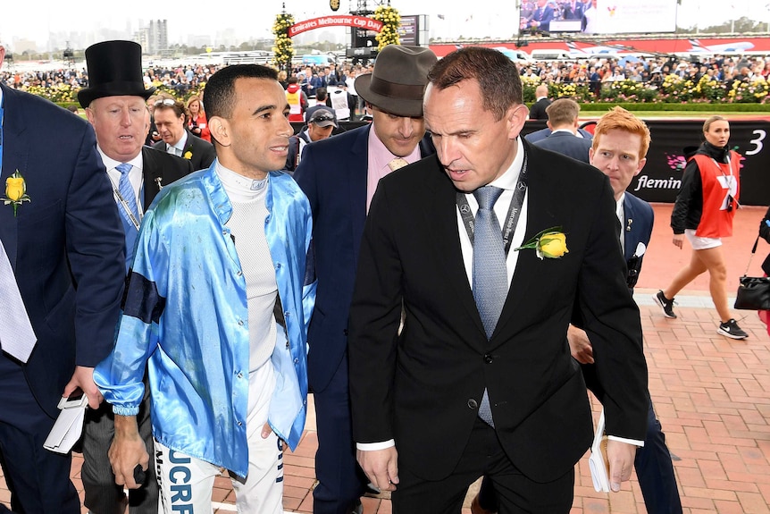Trainer Chris Waller walks with jockey Joao Moreira after he fell while riding Regal Monarch at Flemington.