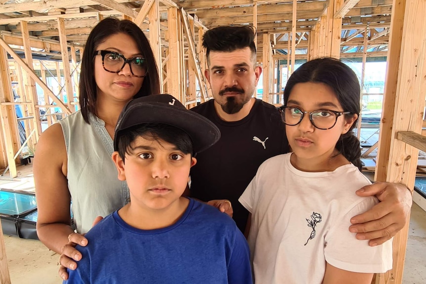 Zainab Akhter and her husband and two children stand inside the frame of their home