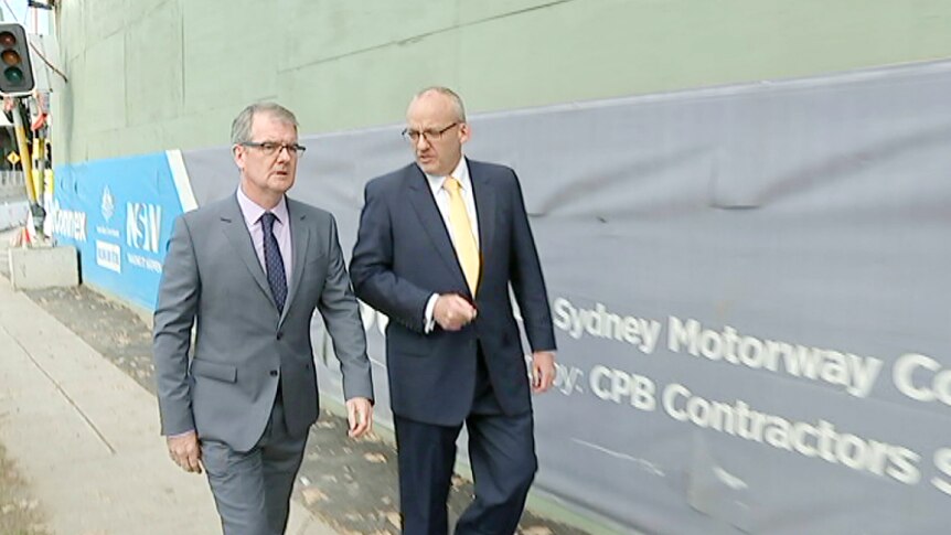 New South Wales Opposition Leader Luke Foley and Labor MP Michael Daley walk past a WestConnex sign.