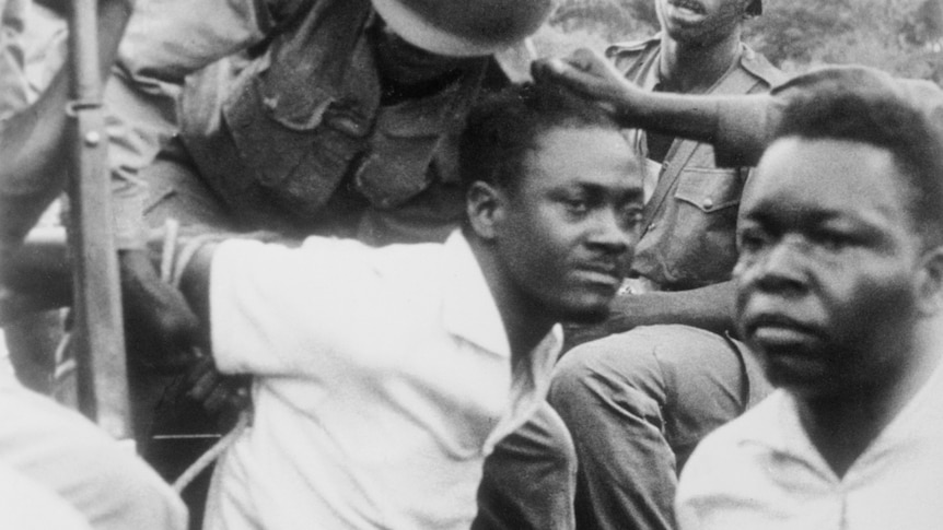 Congolese independence leader Patrice Lumumba being held with hand behind back by soldiers