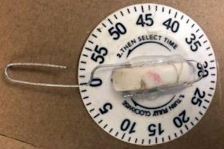A timer device with a paperclip wrapped around it, set at zero minutes