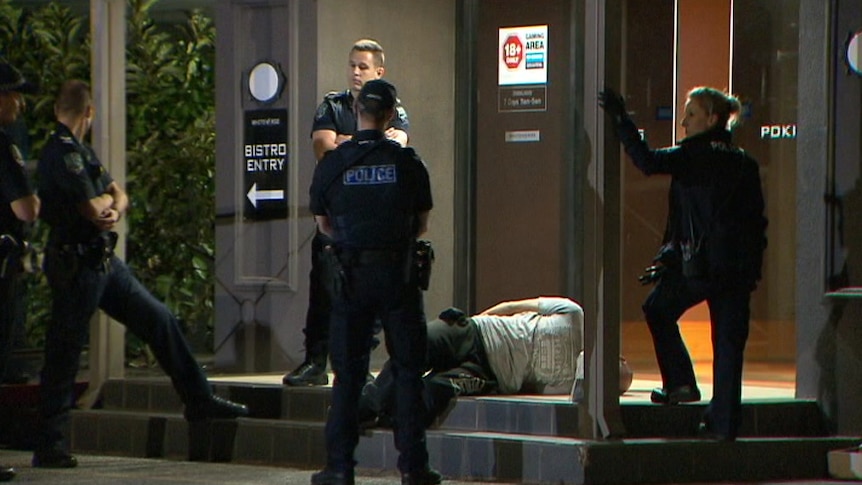 Police stand around a man on the ground at a pub with handcuffs