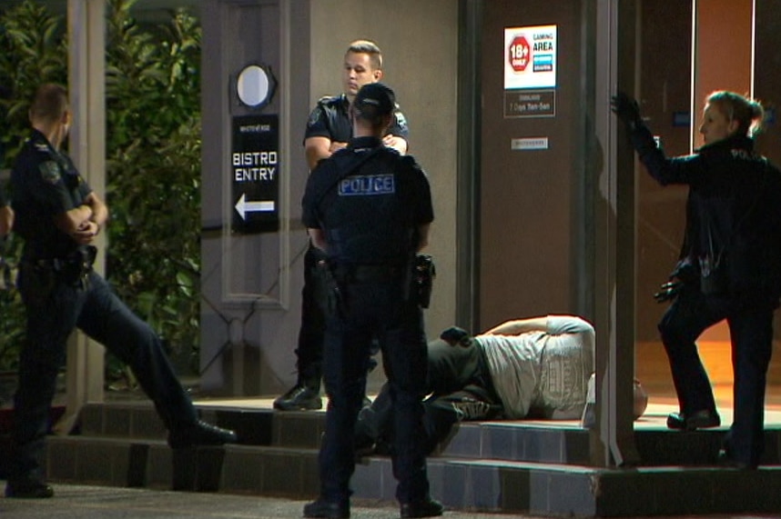 Police stand around a man on the ground at a pub with handcuffs