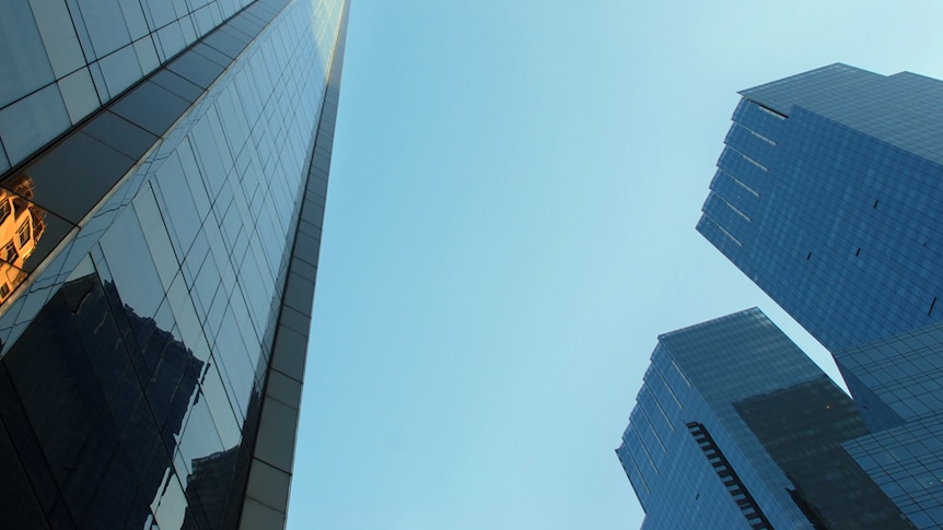 Photo looking up between buildings towards a blue sky.