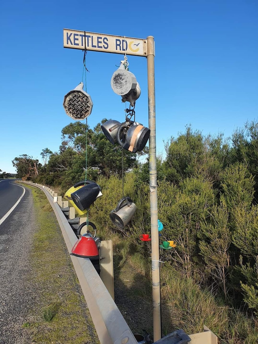 Seven kettles hang on Kettles Road signpost.