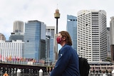 一个戴口罩的路人，背景是悉尼天际线
