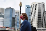 a woman wearng a red mask with the sydney centrepoint tower in the background