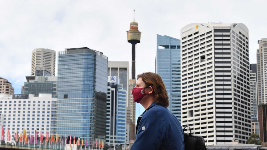 一个戴口罩的路人，背景是悉尼天际线