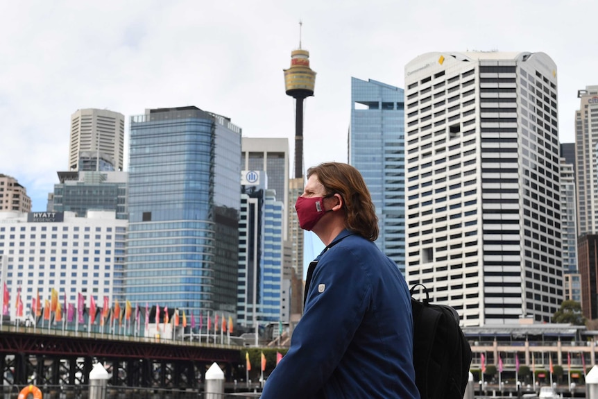 A person walks past a Sydney skyline