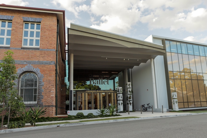 The entrance to Queensland Ballet is sandwiched between a old brick building and a structure with a glass-window facade