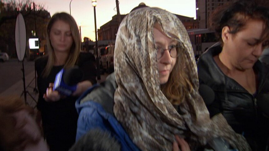 Lisa Barrett leaves Adelaide Magistrates Court with her head covered.