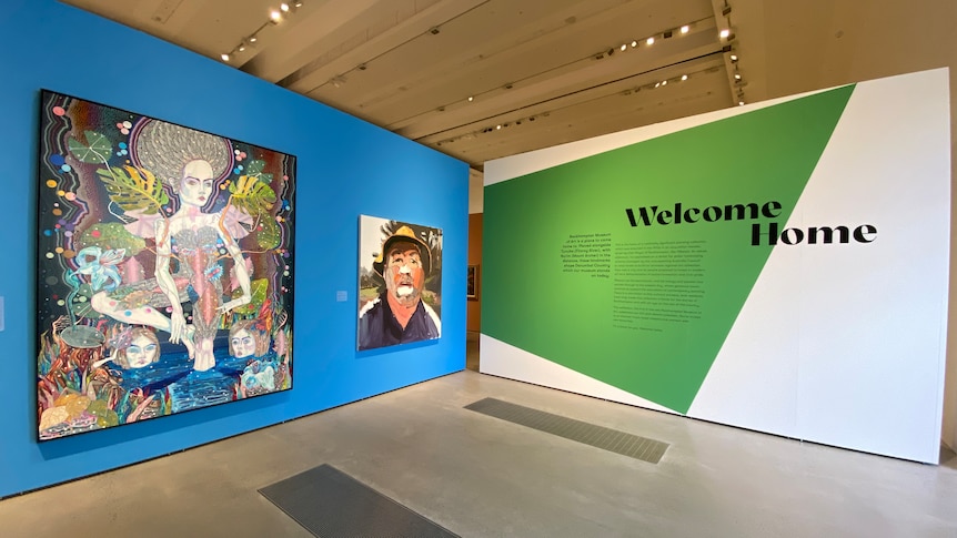 A wide angle shot showing a wall with 'welcome home' printed on it and a blue wall with large portraits