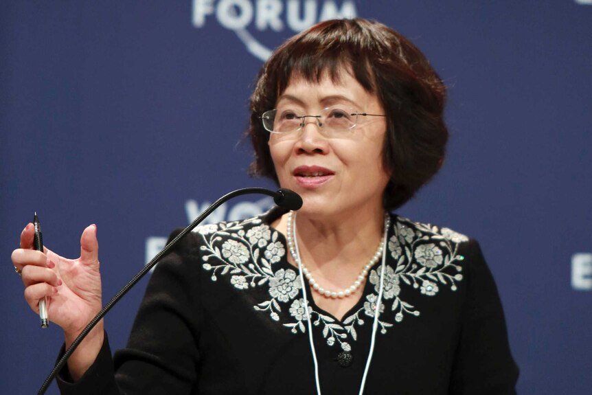 Hu Shuli sitting down, speaking into a microphone with a World Economic Forum banner in the background.