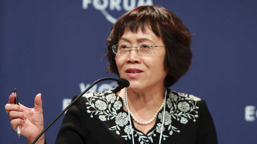 Hu Shuli sitting down, speaking into a microphone with a World Economic Forum banner in the background.