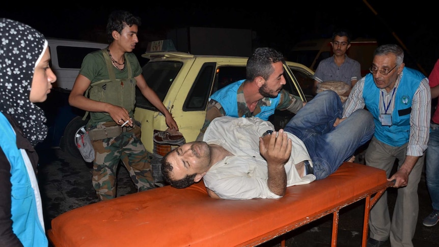 Syrian civil defence members carry a wounded man on a stretcher.