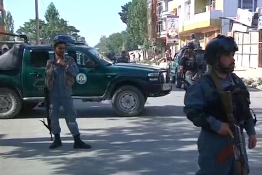 Afghan security personnel inspect the site of a car bomb attack in the western part of Kabul.