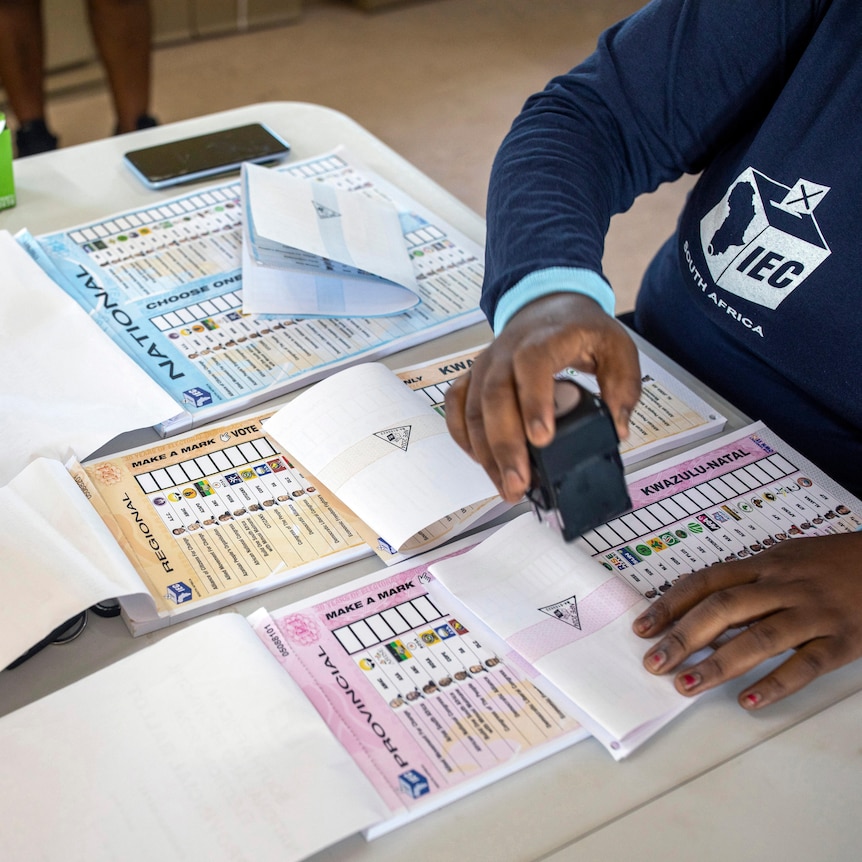close up of ballot papers, and navy sweater with the words "IEC" and "South Africa" printed on them