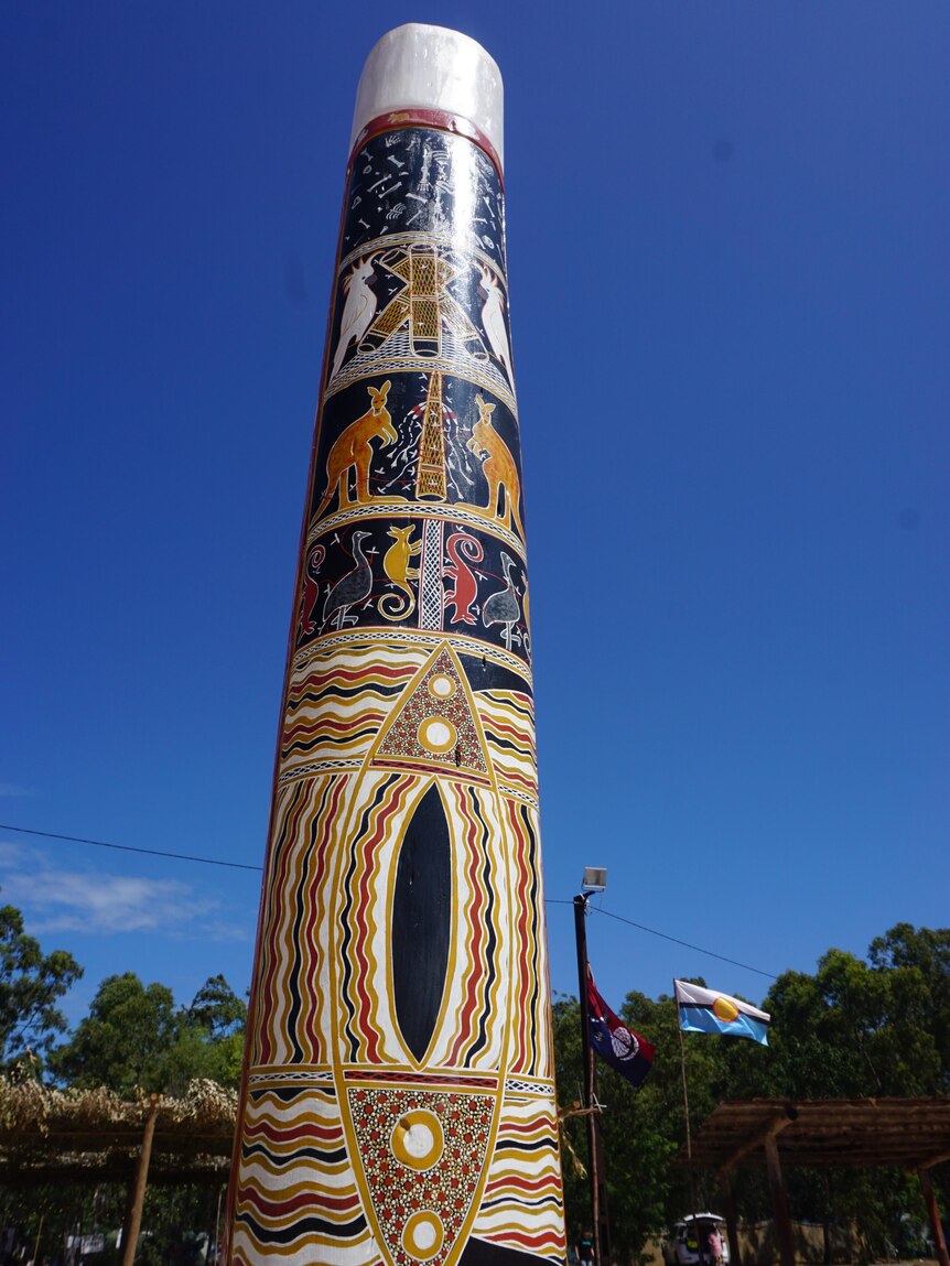 An indigenous totem pole in front of a blue sky.