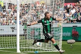 An A-League striker runs away with his arms outstretched as the ball lies in the back of the net.