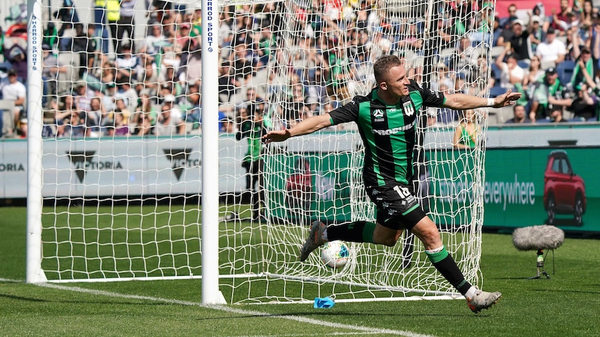 An A-League striker runs away with his arms outstretched as the ball lies in the back of the net.