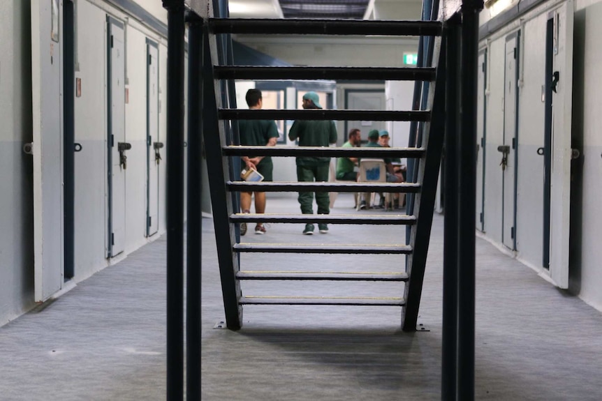 Inmates walk around and talk at a table inside the prison.