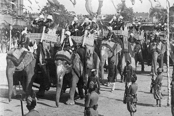 A black and white photo of people riding elephants in New Delhi.