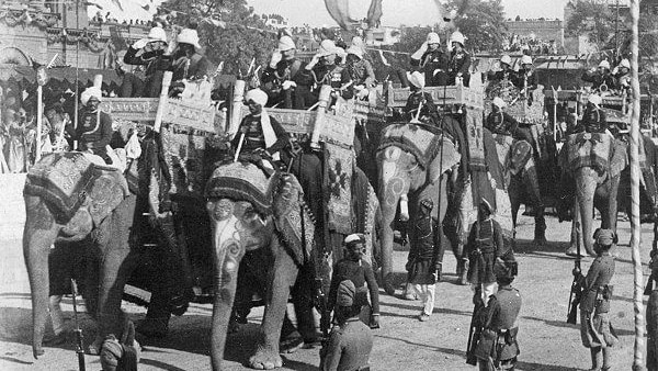 A black and white photo of people riding elephants in New Delhi.