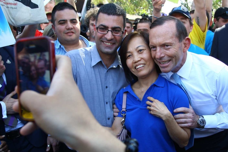 Tony Abbott and Nickolas Varvardis take a photo with a voter